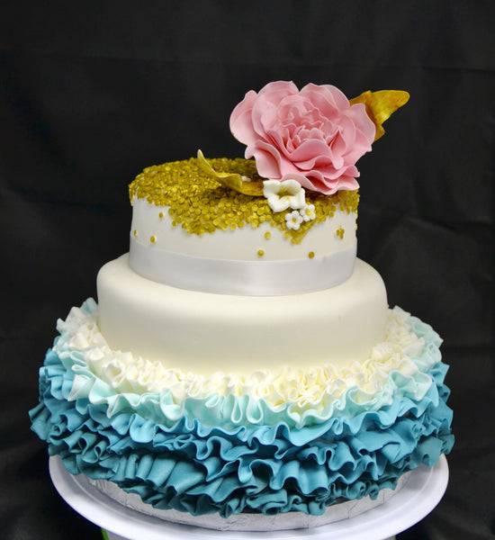 3 TIER WEDDING CAKE WITH BLUE OMBRE RUFFLES AND GOLD SEQUIN WITH A PINK FLOWER ON TOP BY SUGAR STREET BOUTIQUE TORONTO.