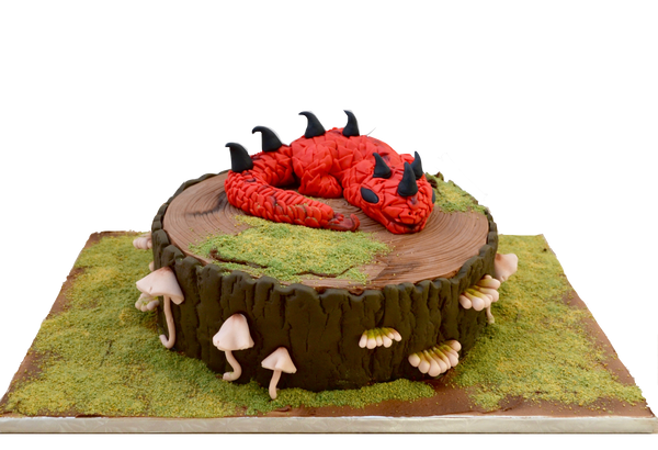 red dragon cake sitting on a edible fondant tree stump and edible fondant mushrooms with edible grass by sugar street boutique toronto.