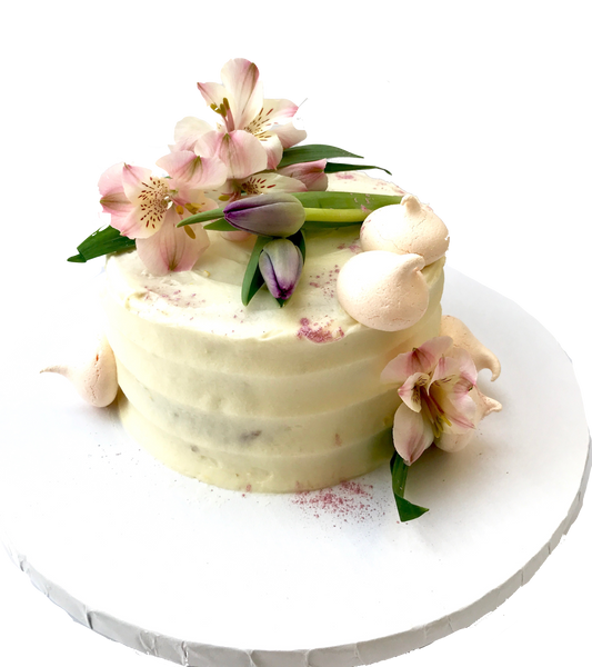 4 layer lemon cake with lemon curd in between layers and iced with a light lemon icing. Decorated with meringues, lillies & tulips by sugar street boutique toronto.