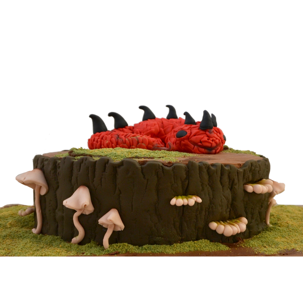 red dragon cake sitting on a edible fondant tree stump and edible fondant mushrooms with edible grass by sugar street boutique toronto.