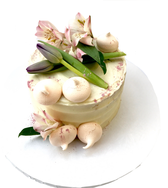 4 layer lemon cake with lemon curd in between layers and iced with a light lemon icing. Decorated with meringues, lillies & tulips by sugar street boutique toronto.